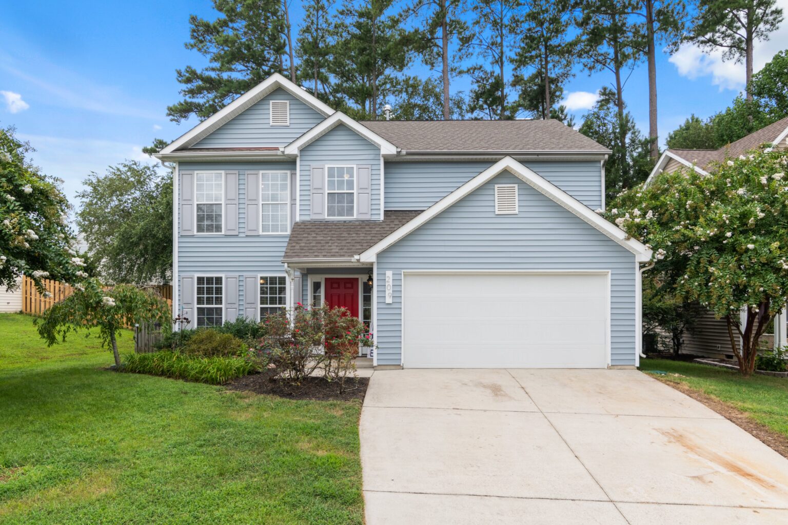 A house with a driveway and trees in the background