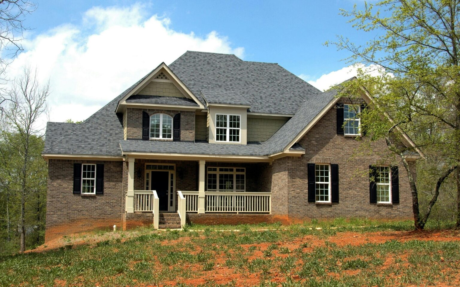 A large brick house with a porch and steps.