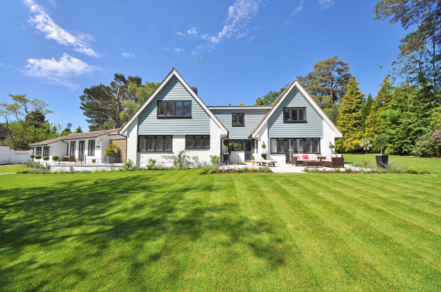 A large white house with green grass on the front lawn.