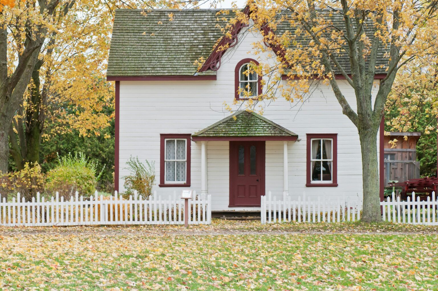 A white house with red trim and green shutters.